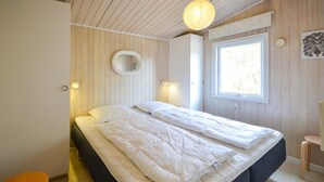 A bedroom with a large bed, wooden walls, a window, and a round mirror. - 4 bedroom lovely home in Thisted (Thisted)