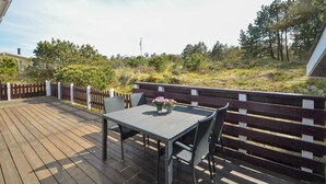 A wooden deck with a table and chairs, surrounded by a wooden fence and a bench. - 4 bedroom lovely home in Thisted (Thisted)