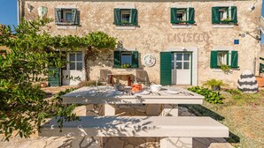 Un edificio rústico con fachada de piedra, contraventanas verdes y un letrero que indica que es un restaurante.