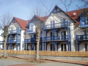 A row of multi-story buildings with balconies, wooden fences, and a clear sky. - Villa Quisisana in the Kurstraße (EC) - Apartment Villa Quisisana (Graal-Müritz)
