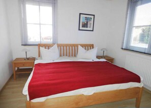 A bedroom with a wooden bed, white bedding, two bedside tables, and a framed picture on the wall.