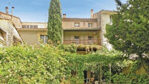 Una vila tradicional de tipus mediterrani amb un pati interior, amb un edifici central que té un balcó i una pèrgola coberta de vïnia.