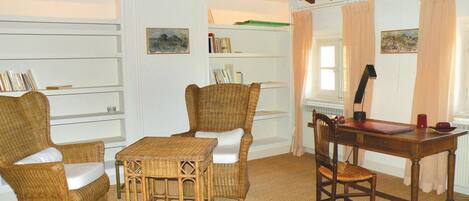 A cozy room with wicker furniture, a wooden desk, and bookshelves.