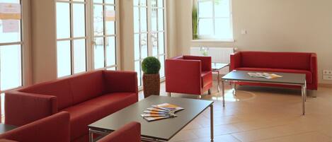 A modern living room with a red sofa, a red armchair, a coffee table, and a small side table with a plant.