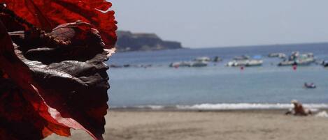 A beach with boats and people in the water.