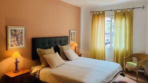 Una habitación de hotel con una cama, dos lámparas de noche, una silla y una ventana con cortinas.