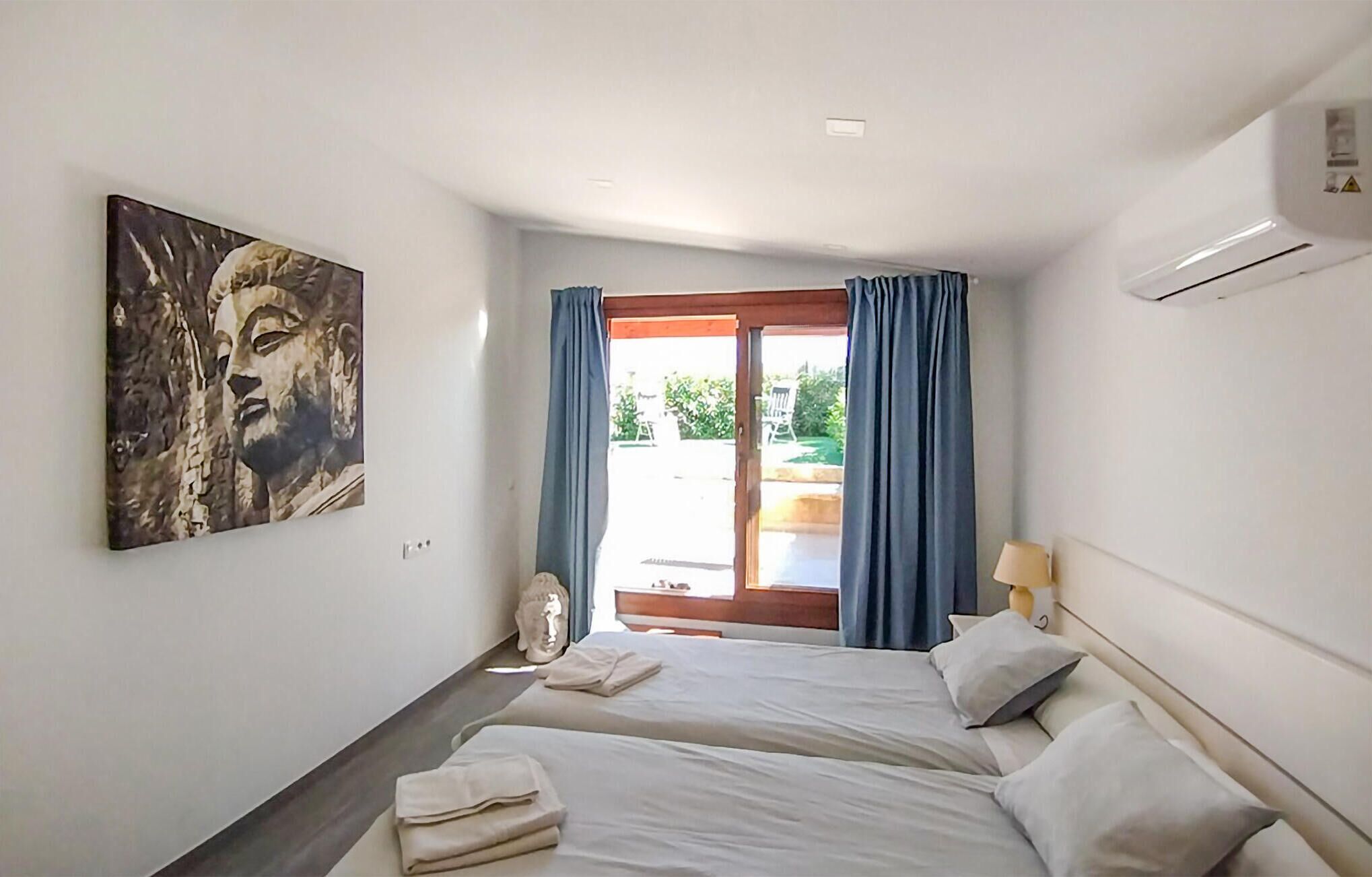 Une chambre d’hôtel avec deux lits, un tableau au mur, une fenêtre avec des rideaux et une vue sur l’extérieur.