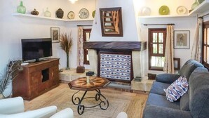 Una sala de estar con televisor, sofá y objetos decorativos en estanterías.