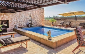 A swimming pool with stone walls, lounge chairs, and a pergola. - Amazing home in Manacor (Manacor)