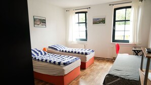Une chambre avec deux lits, un bureau et une chaise.