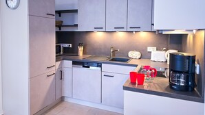 A modern kitchen with a dishwasher, microwave, toaster, and coffee maker. - 3 Room H 7 - Wohnpark Binz (with indoor pool) (Binz)