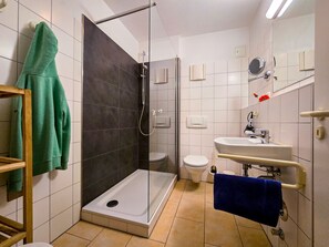 A modern bathroom with a glass-enclosed shower, a toilet, a sink with a mirror, and towels on a rack. - 3 Room H 7 - Wohnpark Binz (with indoor pool) (Binz)