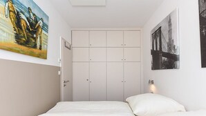 A bedroom with a bed, a wardrobe, and two paintings on the walls. - Holiday house Watt'n Huus (Dornum)