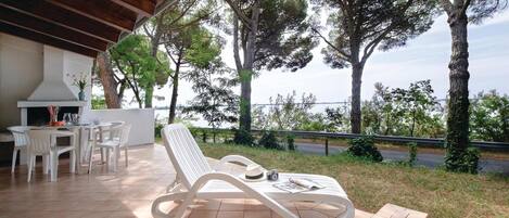 Un espacio al aire libre con techo, con una mesa y sillas, con vista a un cuerpo de agua y árboles.