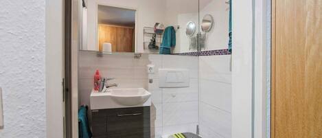 A compact bathroom with a white sink, a mirror, and a toilet.