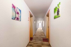A hallway with wooden flooring, two doors, and two framed artworks on the walls. - Holiday apartment with shared balcony (Todtmoos)