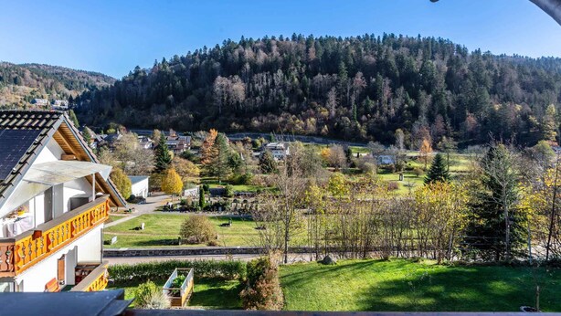 Une vue d’un village avec un bâtiment remarquable doté d’un balcon, et une montagne en arrière-plan.