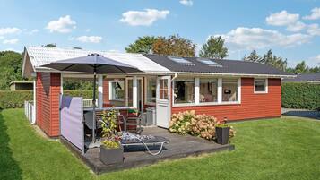 Een gelijkvloers huis met een overdekt terras, een kleine tuin en een raam met uitzicht op de tuin.