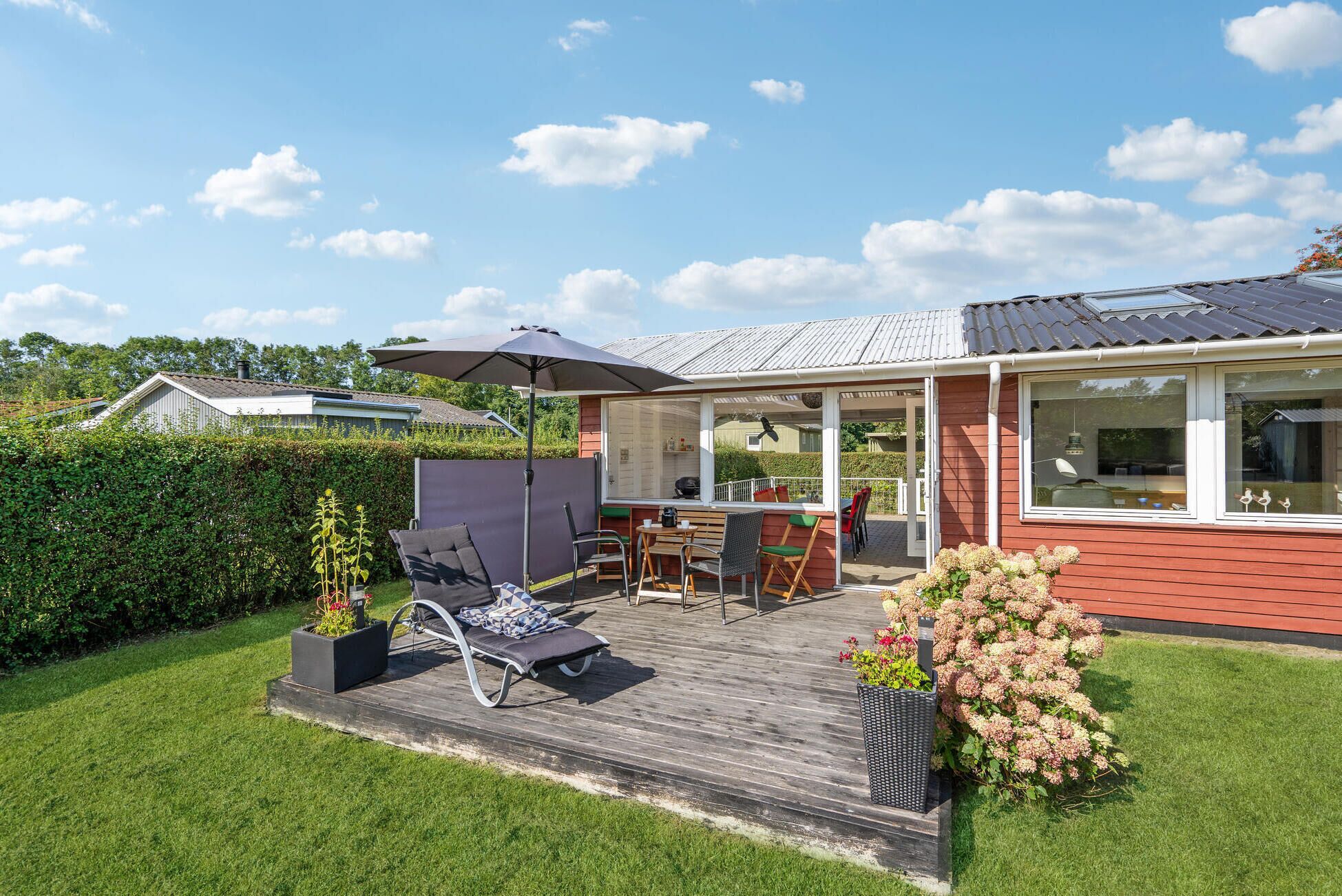 Une terrasse en bois avec des meubles d’extérieur, un patio couvert et une vue sur le paysage environnant.