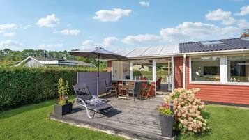 Een houten terras met buitenmeubilair, een overdekte patio en uitzicht op het omliggende landschap.