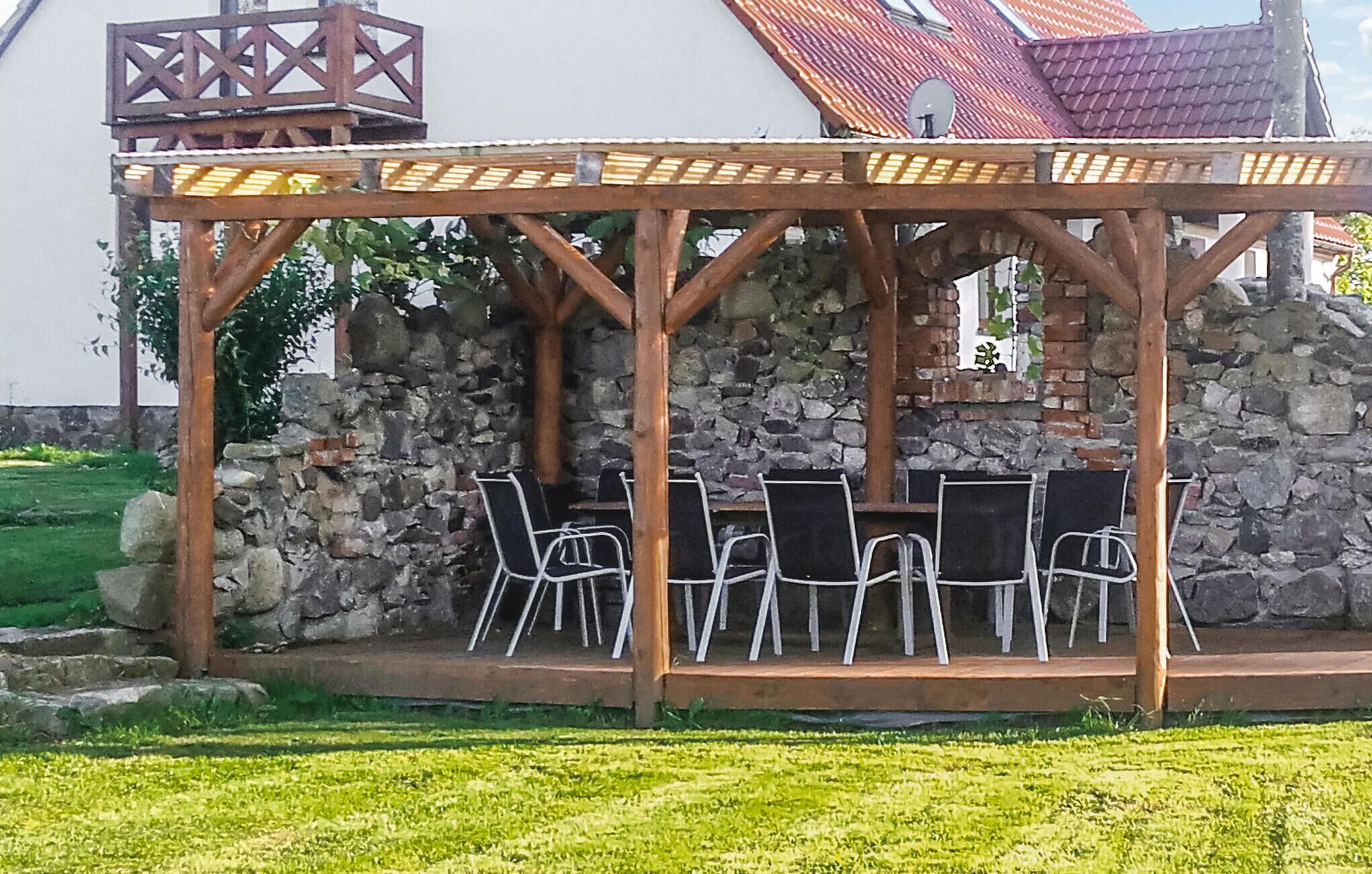 Un espace extérieur aménagé, abrité et doté de murs en pierre et d’une pergola en bois.