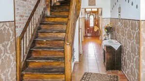 A wooden staircase leading to a room with a patterned wall and a small table with a vase of flowers. - Nice home in Pl-76-113 Postomino (Pl-76-113 Postomino)