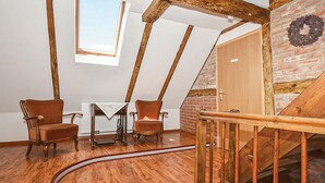 A loft bedroom with exposed wooden beams, a brick wall, a wooden door, and a small table with a chair. - Nice home in Pl-76-113 Postomino (Pl-76-113 Postomino)