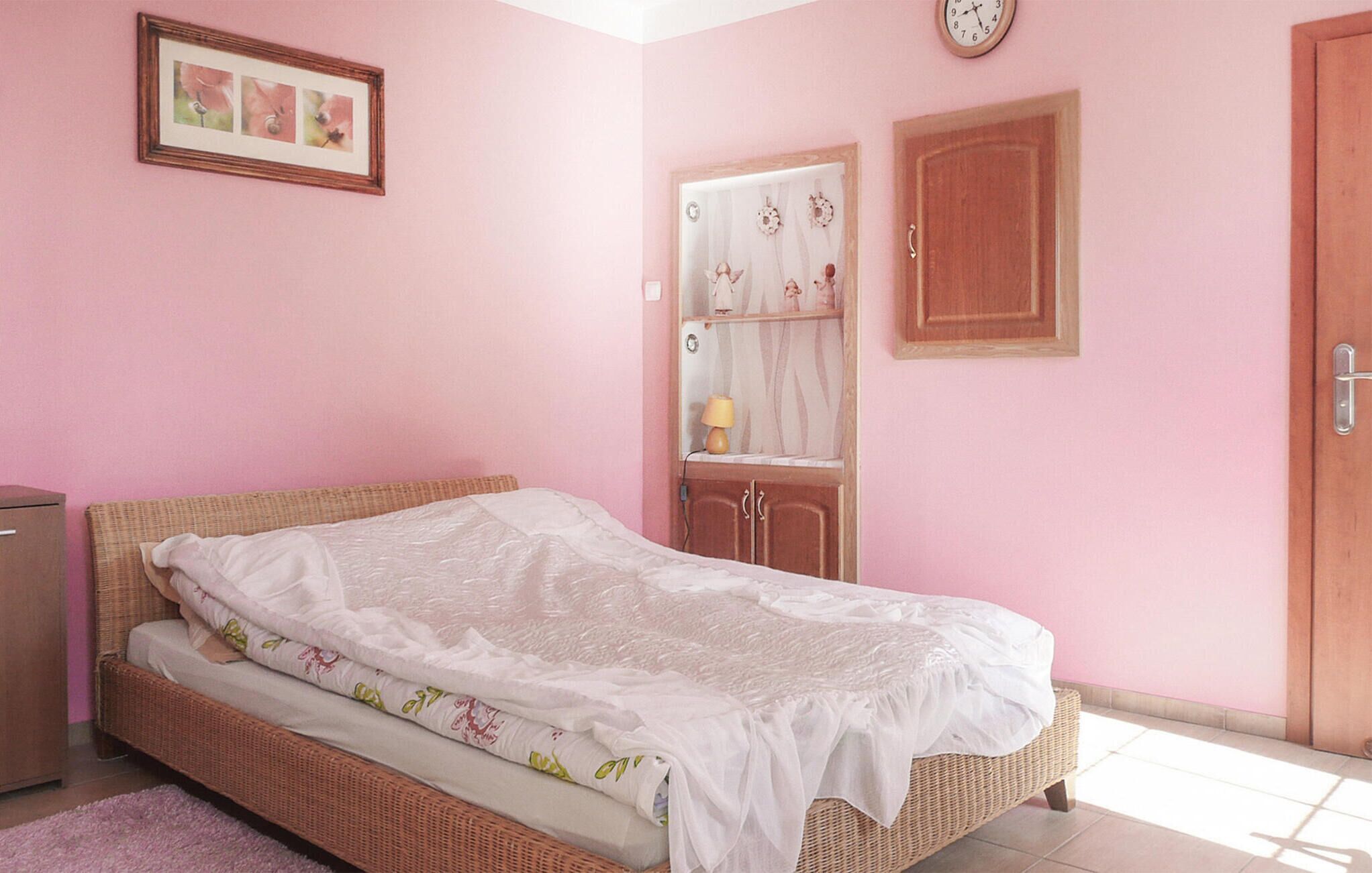 A bedroom with a single bed, a dresser, a wardrobe, and a clock on the wall.