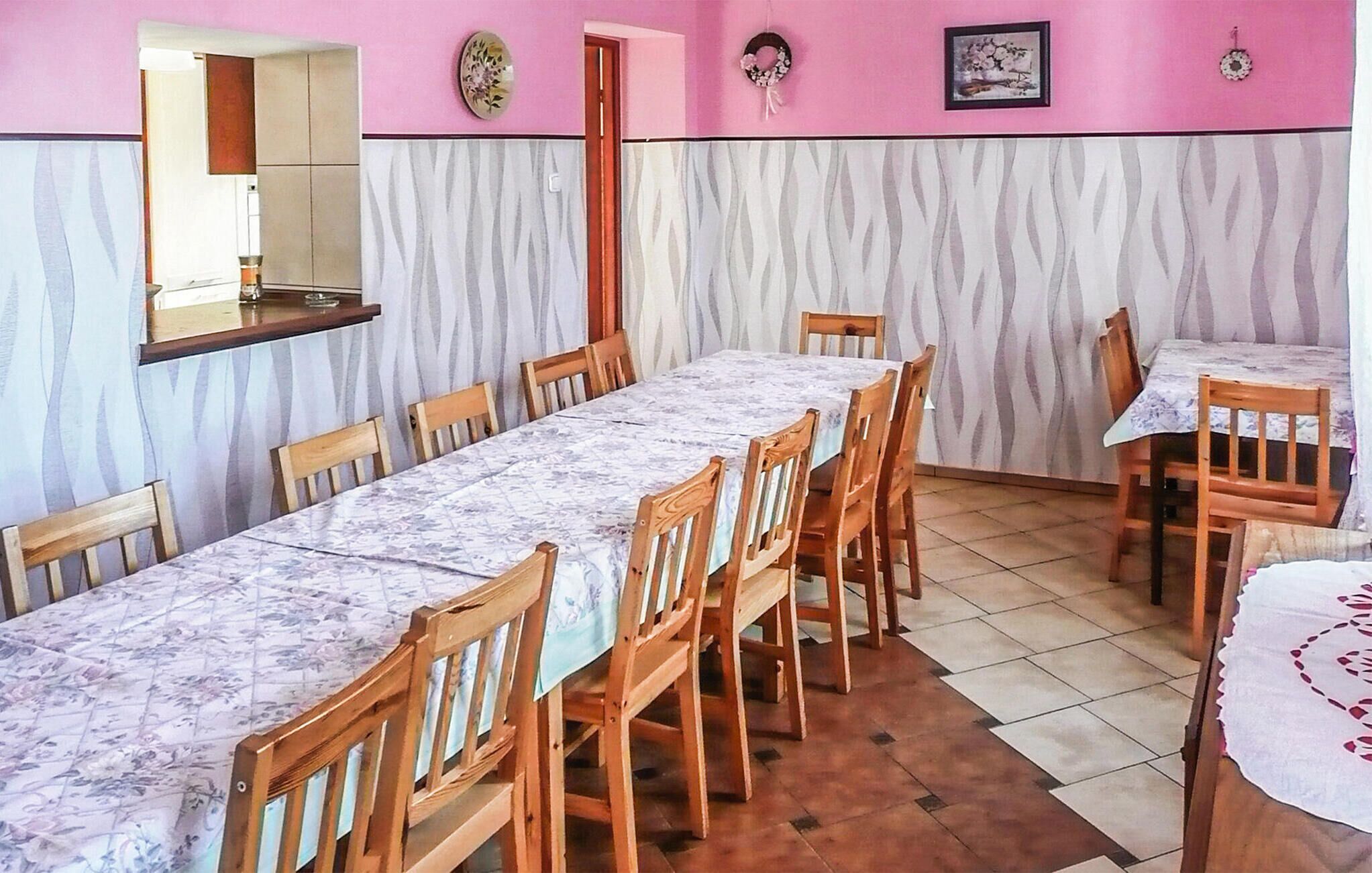 A dining area with a long table and chairs, a mirror, and decorative wall elements.