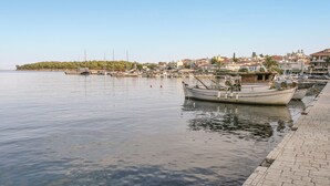 A marina with boats docked, a calm water surface, and a distant shoreline with buildings. - Soleiliosonne Haus Zeus (Ermioni)