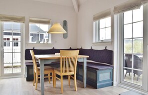 Un espace repas comprenant une table et des chaises en bois, un banc et un luminaire suspendu.