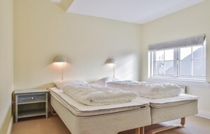 Une chambre avec deux lits, une table de chevet et une fenêtre donnant sur un beau paysage.