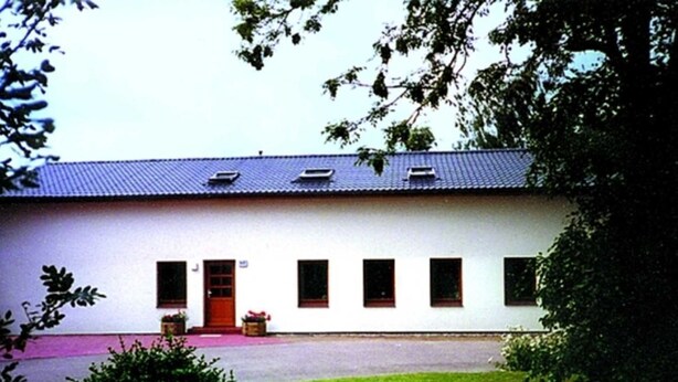 A white building with a red door, multiple windows, and a paved driveway. - Apartment 2 - Budach: Country vacation at the gates of Flensburg (Handewitt)
