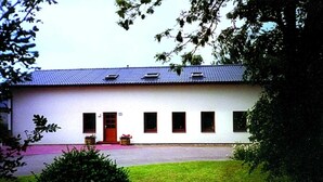 A white building with a red door, multiple windows, and a blue roof. - Apartment 2 - Budach: Country vacation at the gates of Flensburg (Handewitt)