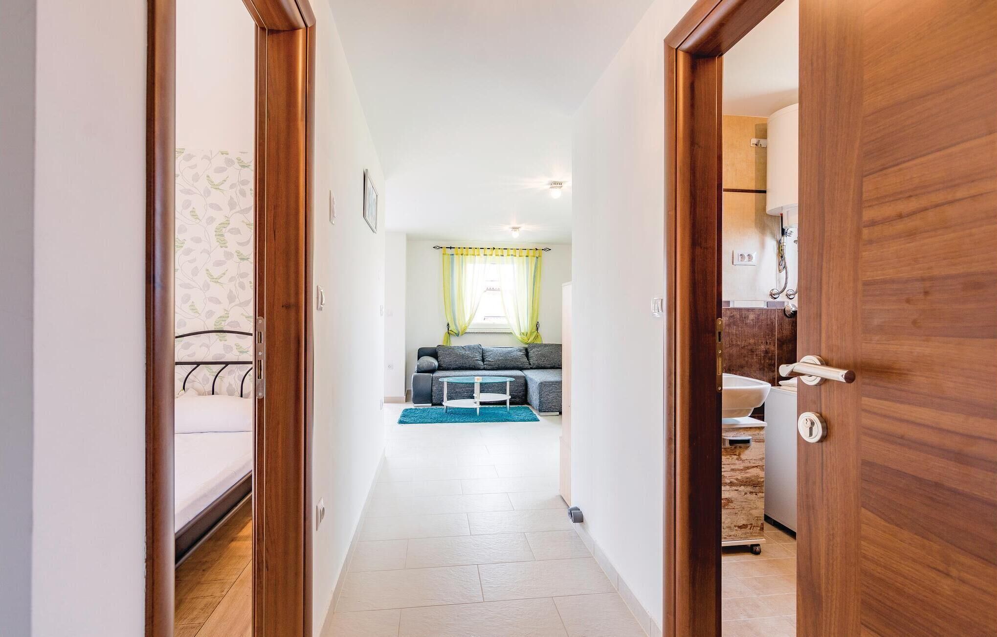 A hallway leading to a living area with a sofa, a small table, and a view of a bathroom.