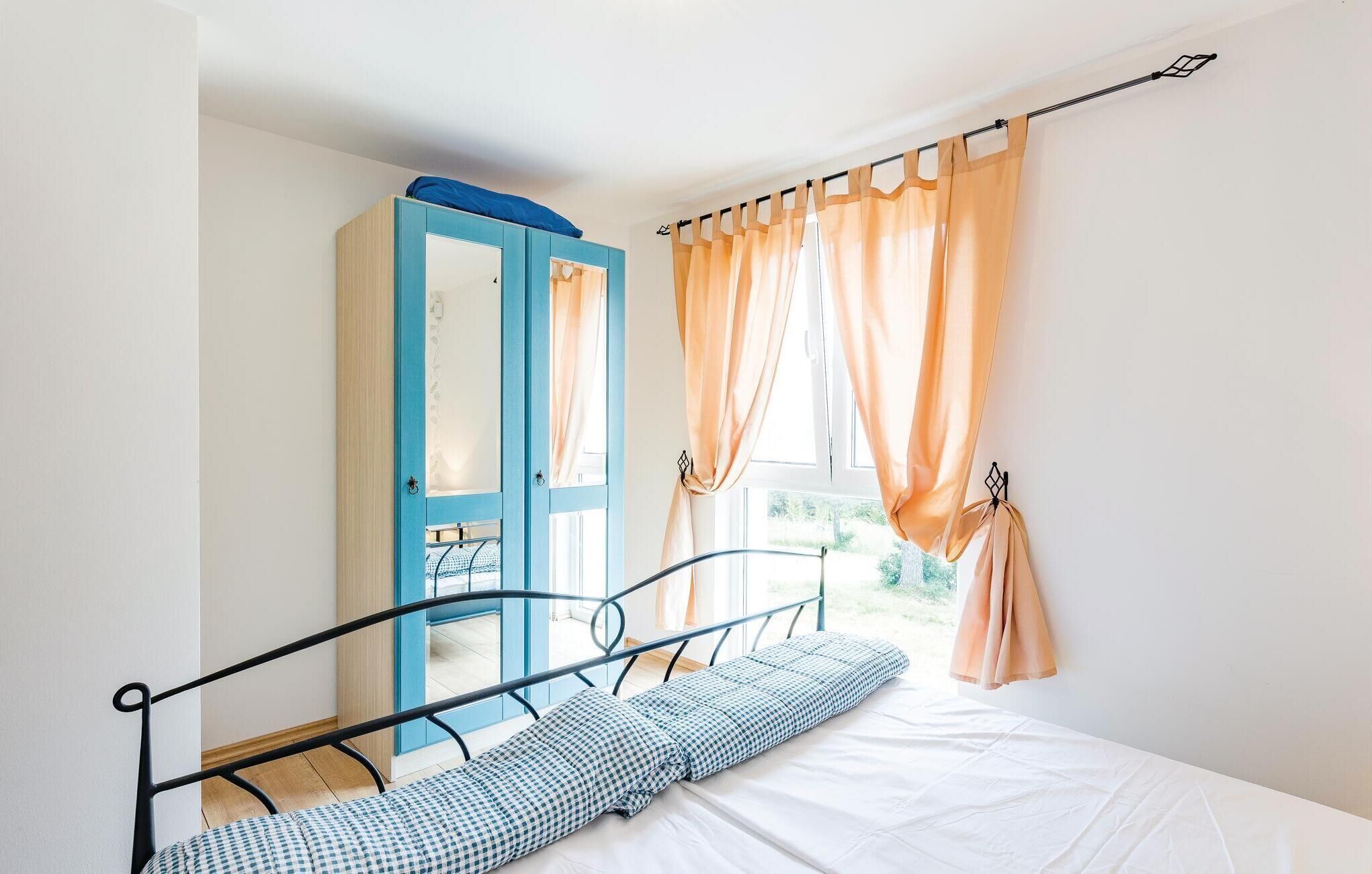 Ein Schlafzimmer mit Bett, Kleiderschrank und einem fenster mit Vorhängen.