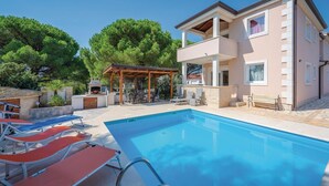 A poolside area with lounge chairs, a barbecue, and a covered seating area. - Beautiful apartment in Valbandon (Valbandon)