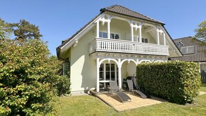 A two-story house with a balcony, a covered porch, and a well-maintained lawn. - Haus Rügenwelle Whg. 04 1st floor with balcony/fireplace - W: Haus Rügenwelle with 4 (Baabe)