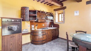 A rustic kitchen with a wooden stove, a coffee machine, and a large wooden barrel.