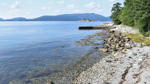 A clear lake with a rocky shoreline and a small island in the distance. - Cozy home in Fusa with sauna (Fusa)
