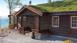 A wooden cabin with a porch, a small deck, and a view of the water. - Cozy home in Fusa with sauna (Fusa)