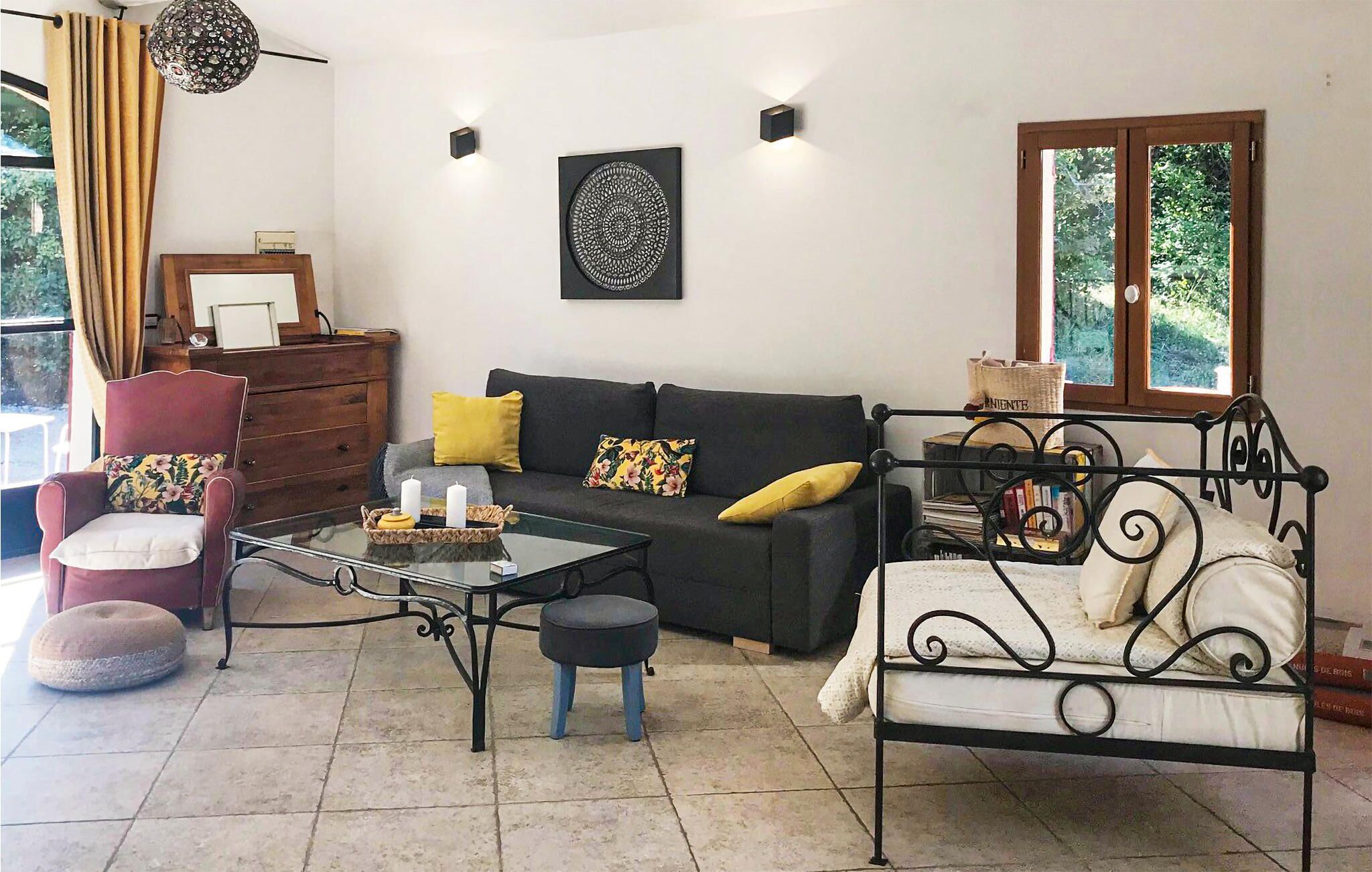 Una sala de estar acogedora con un sofá, una silla, una mesita y una estructura de cama de metal.