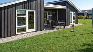 Ein modernes Gebäude mit einer Terrassenfläche, komplett mit Tisch und Stühlen.