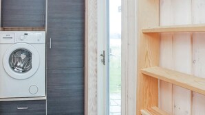 Ein Waschraum mit einer Waschmaschine mit Frontlader, einem dunklen Holzschrank und einer Holzregaleinrichtung.