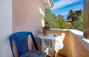 Ein Balkon mit einem punktierten Tisch, einer Topfpflanze und einem blauen Stuhl.