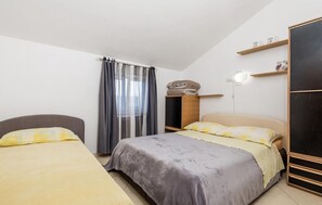 Ein Schlafzimmer mit zwei Betten, einem Kleiderschrank, einem Schreibtisch und einem Stuhl.