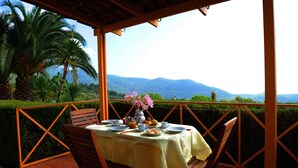 A table set outdoors with a view of mountains and palm trees.