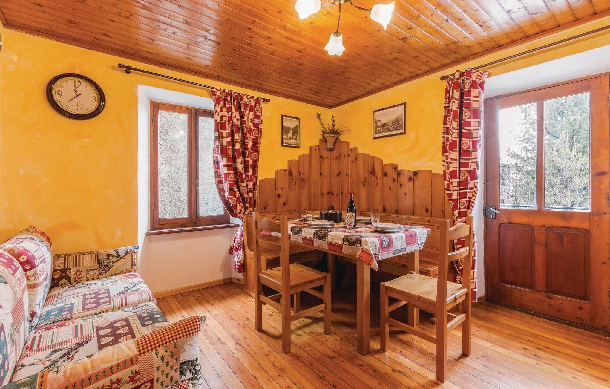 A cozy dining area with a wooden table set for two, a wooden bench, and a clock on the wall.
