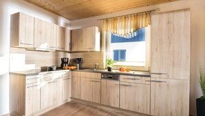 Una cocina moderna con armarios de madera, horno empotrado y ventana con vistas al cielo.
