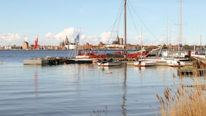 Un puerto con barcos amarrados, una bandera y un edificio al fondo.